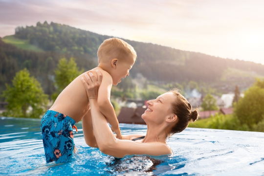 Happy mom swimming with young child