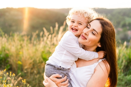 Happy mother hugging her son at sunset