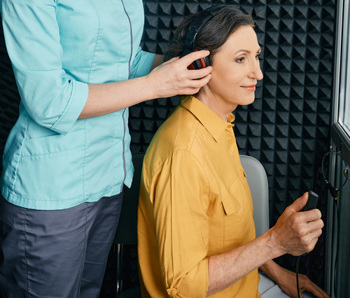 Mature woman getting ready for a hearing test in a hearing booth
